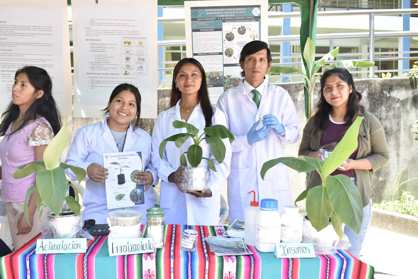 Estudiantes con plantas y material de laboratorio en su stand