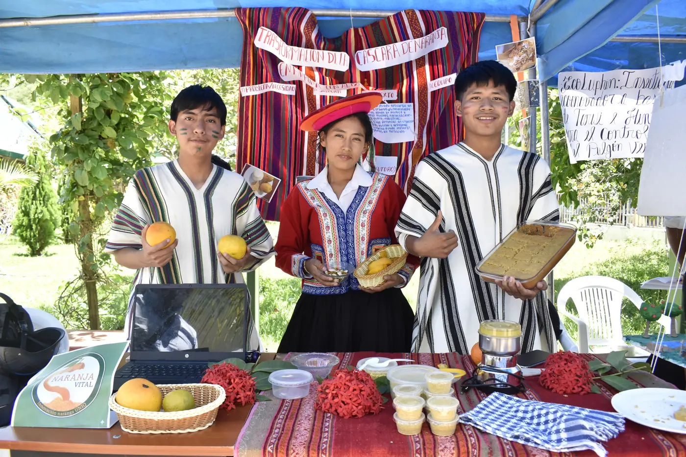 Estudiantes con vestimenta tradicional en un stand con frutas y postres